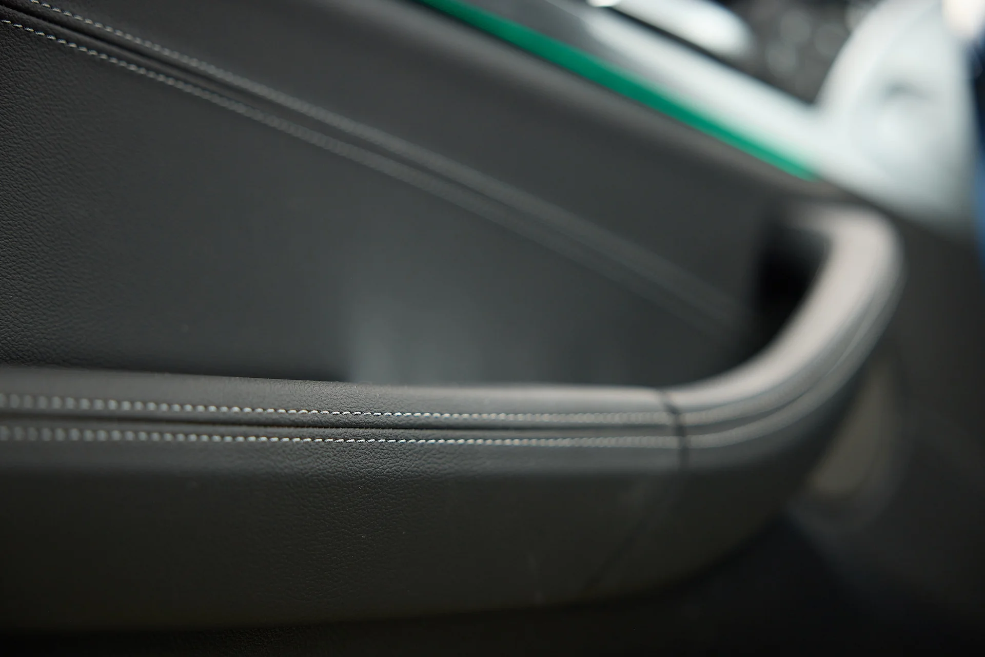 Nahaufnahme eines Autotürgriffs mit sichtbaren Nähten auf dem Leder