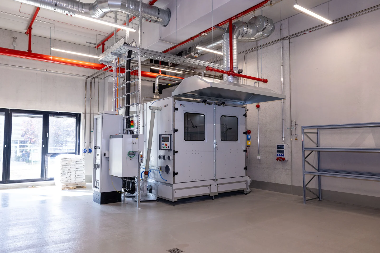 Industrielle Anlage in einem modernen, sauberen Raum mit Lüftungsrohren und großer Maschine.