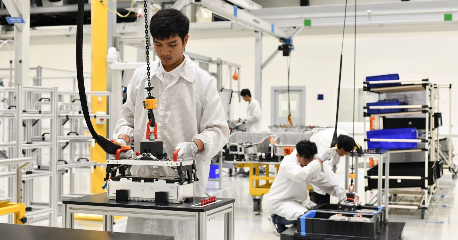 The picture shows DRÄXLMAIER production employees in battery production in Chonburi. They are wearing white coats.