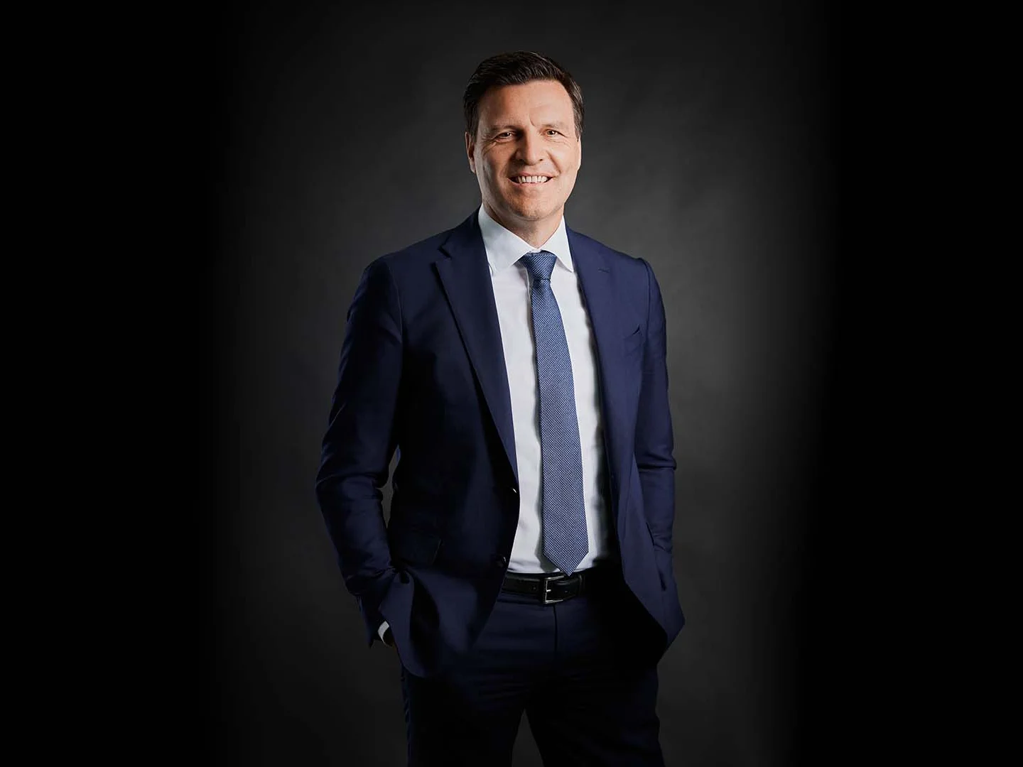 Der Vice Chairman der DRÄXLMAIER Group lächelt in die Kamera. Er trägt einen dunkelblauen Anzug.