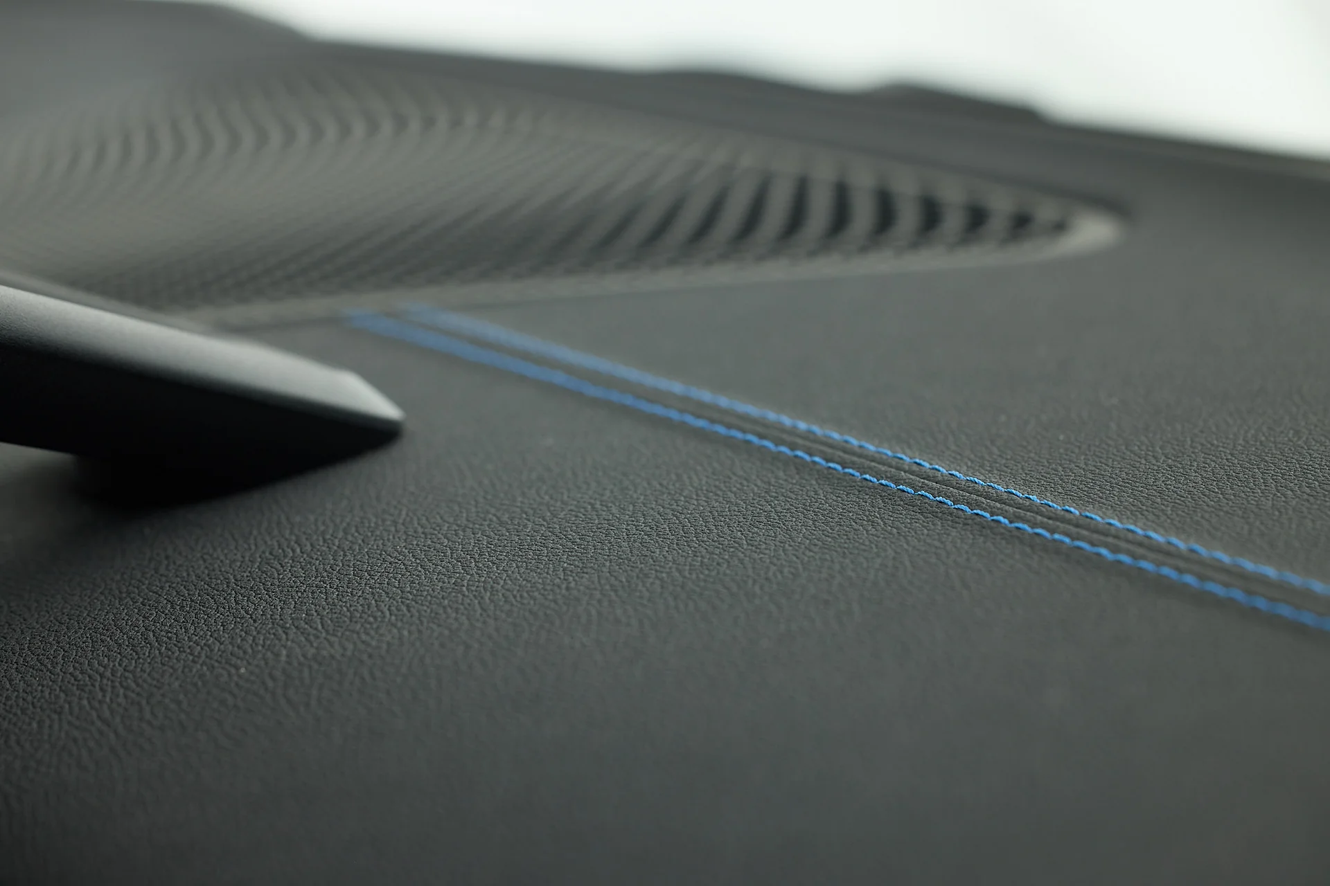 Nahaufnahme einer Interieurkomponente aus Leder mit blauen Nähten.