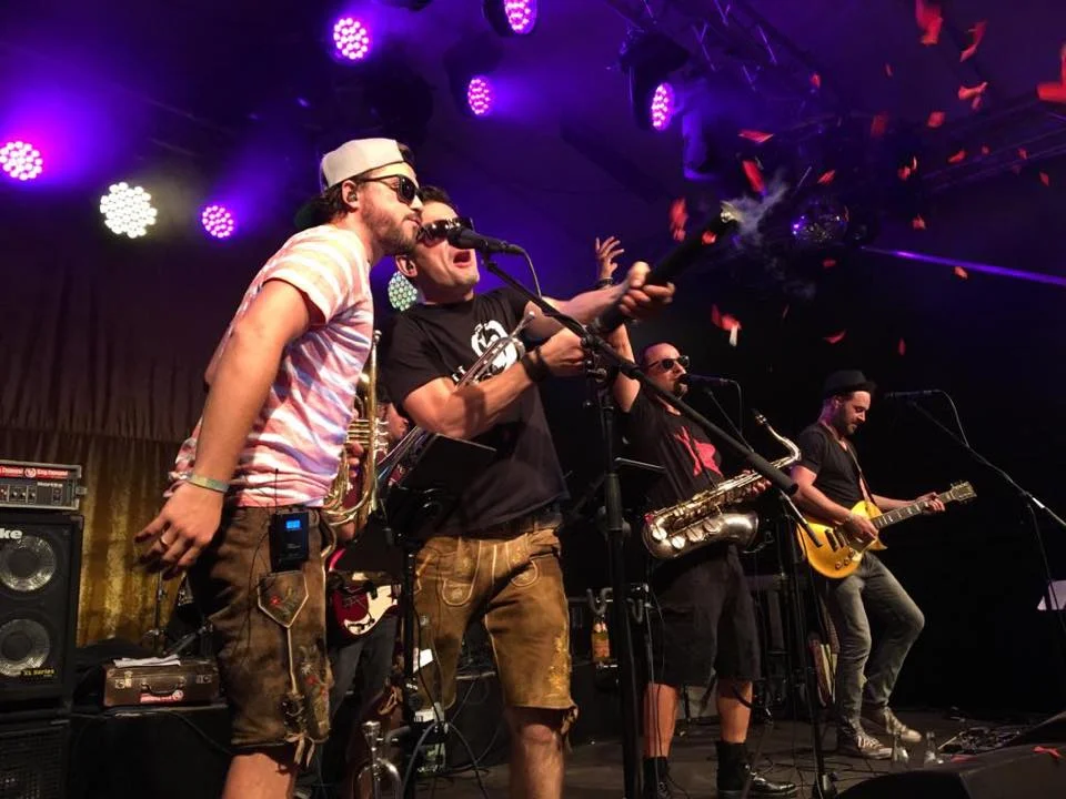 An employee stands on a stage behind the microphone with his band.