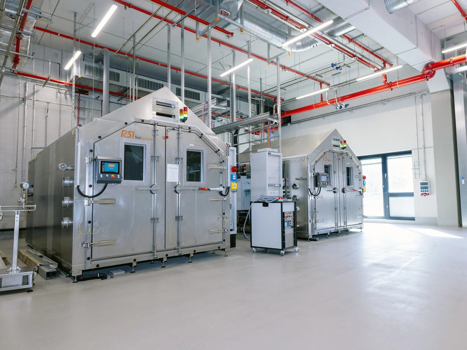 Große Industriemaschine in einer geräumigen Anlage mit hohen Decken und verschiedenen Rohren und Kabeln.