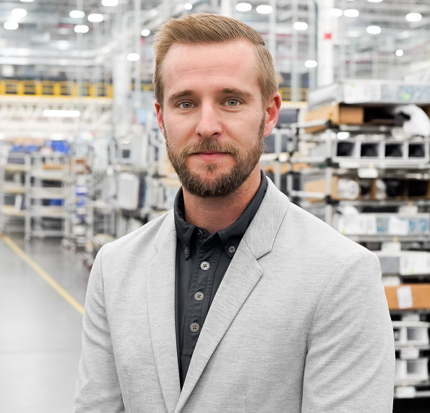 A man in a light grey suit smiles at the camera.